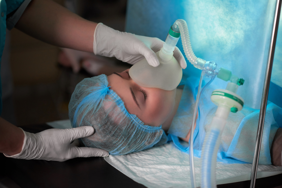 Cropped shot of a nurse holding oxygen mask on a female patient during surgery medicine healthcare professionalism help concept.